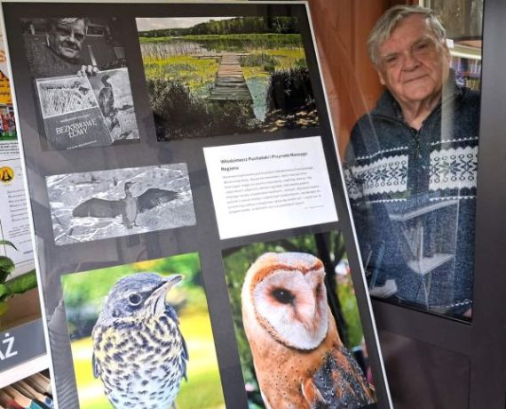 Leszek Machocki - autor zdjęć - pozuje, stojąc obok swojej wystawy