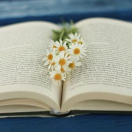 Otwarta książka z bukietem kwiatów na niebieskim tle