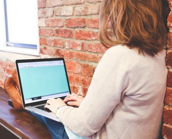 siedząca kobieta z laptopem na kolanach