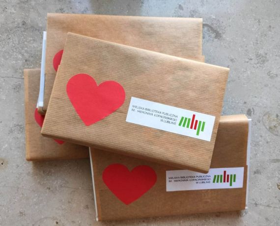 kilka książek opakowanych w szary papier z logo MBP i czerwonym serduszkiem